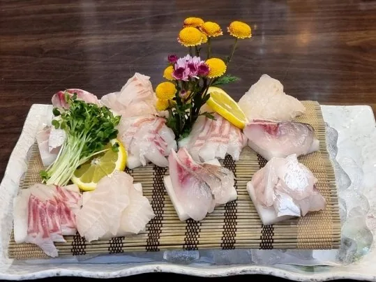 얼음 위 대발에 담은 흰살 생선회 — 꽃·레몬·새싹 장식